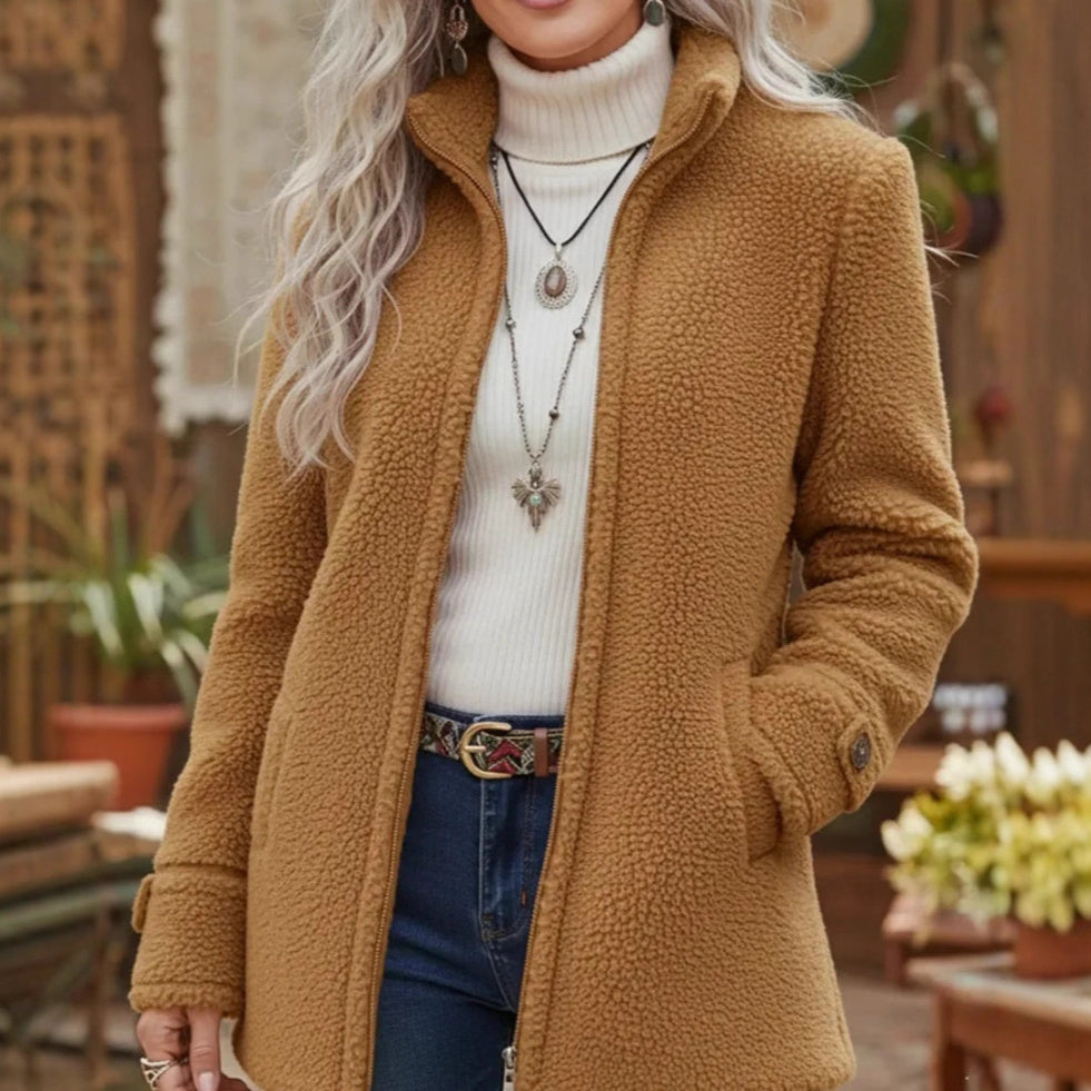 Person wearing a brown teddy coat with a blurred indoor background