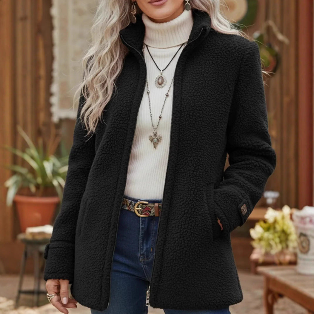 Person wearing a black coat over a white turtleneck sweater with a blurred background