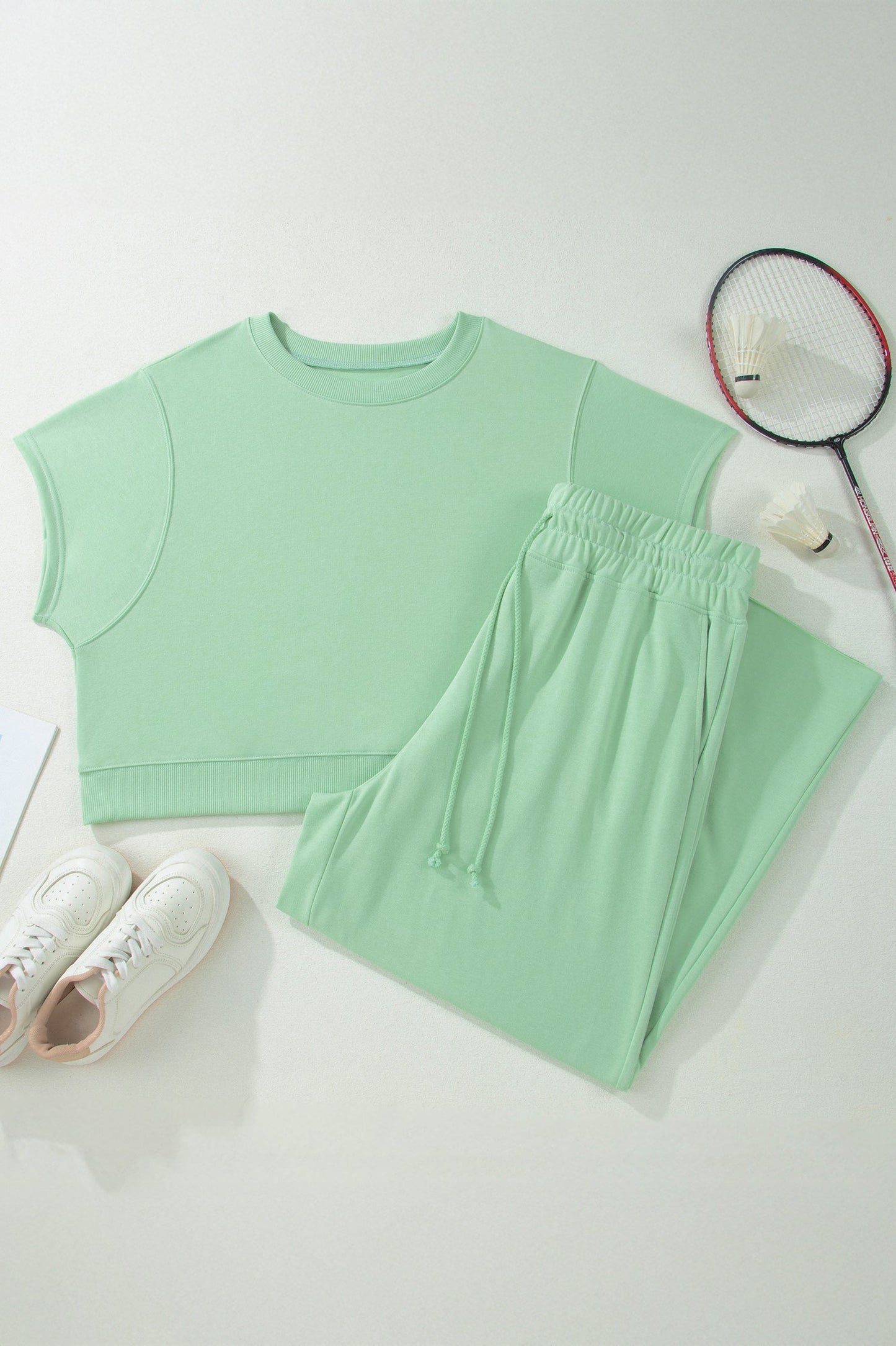 Mint green sleeveless top and pants with a badminton racket on a light gray background