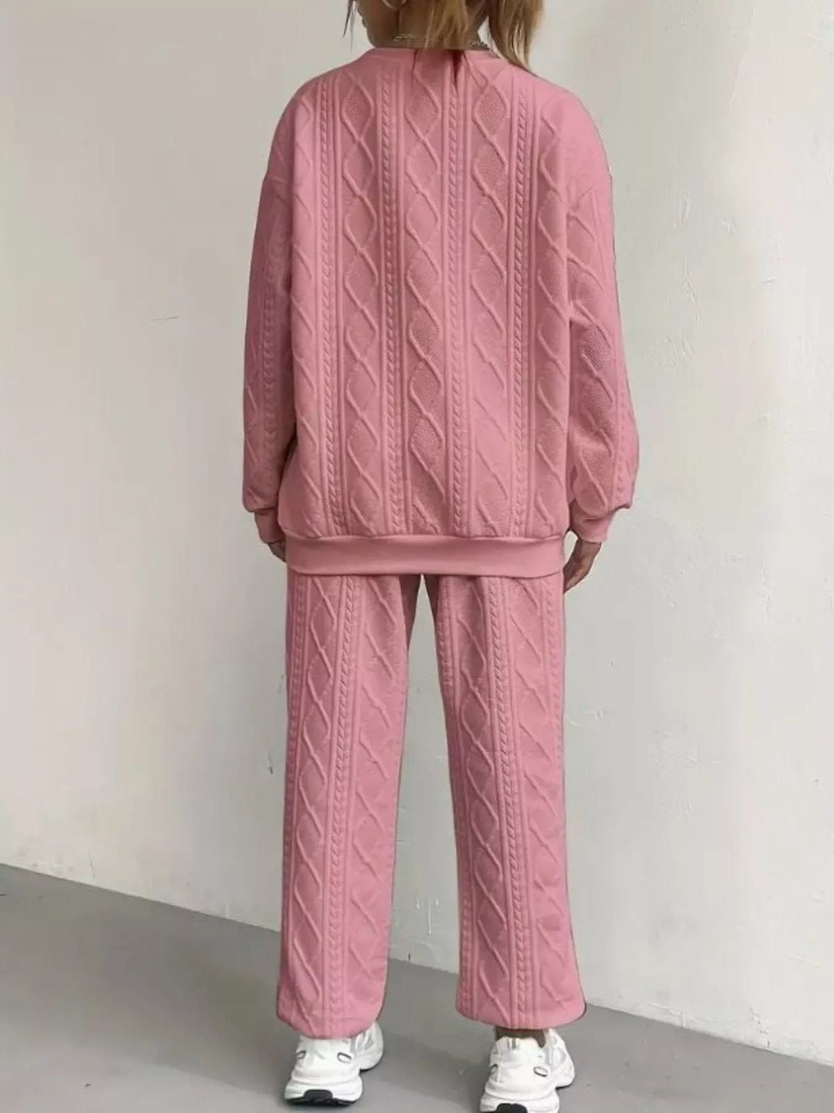 Person wearing a pink textured tracksuit against a plain background