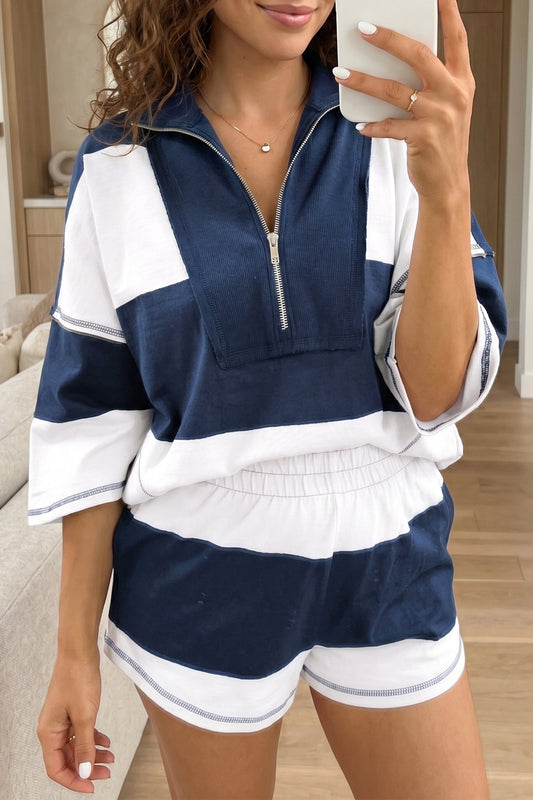 Woman taking a selfie wearing a navy and white outfit indoors.