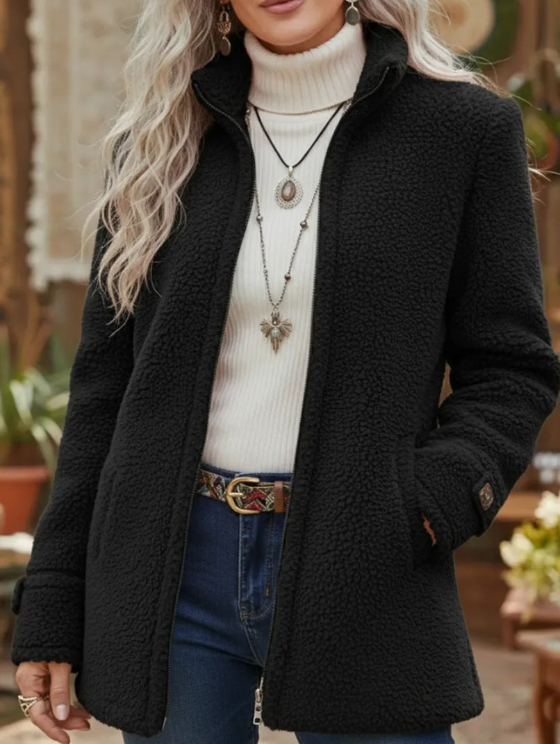 Person wearing a black coat over a white sweater with a blurred background