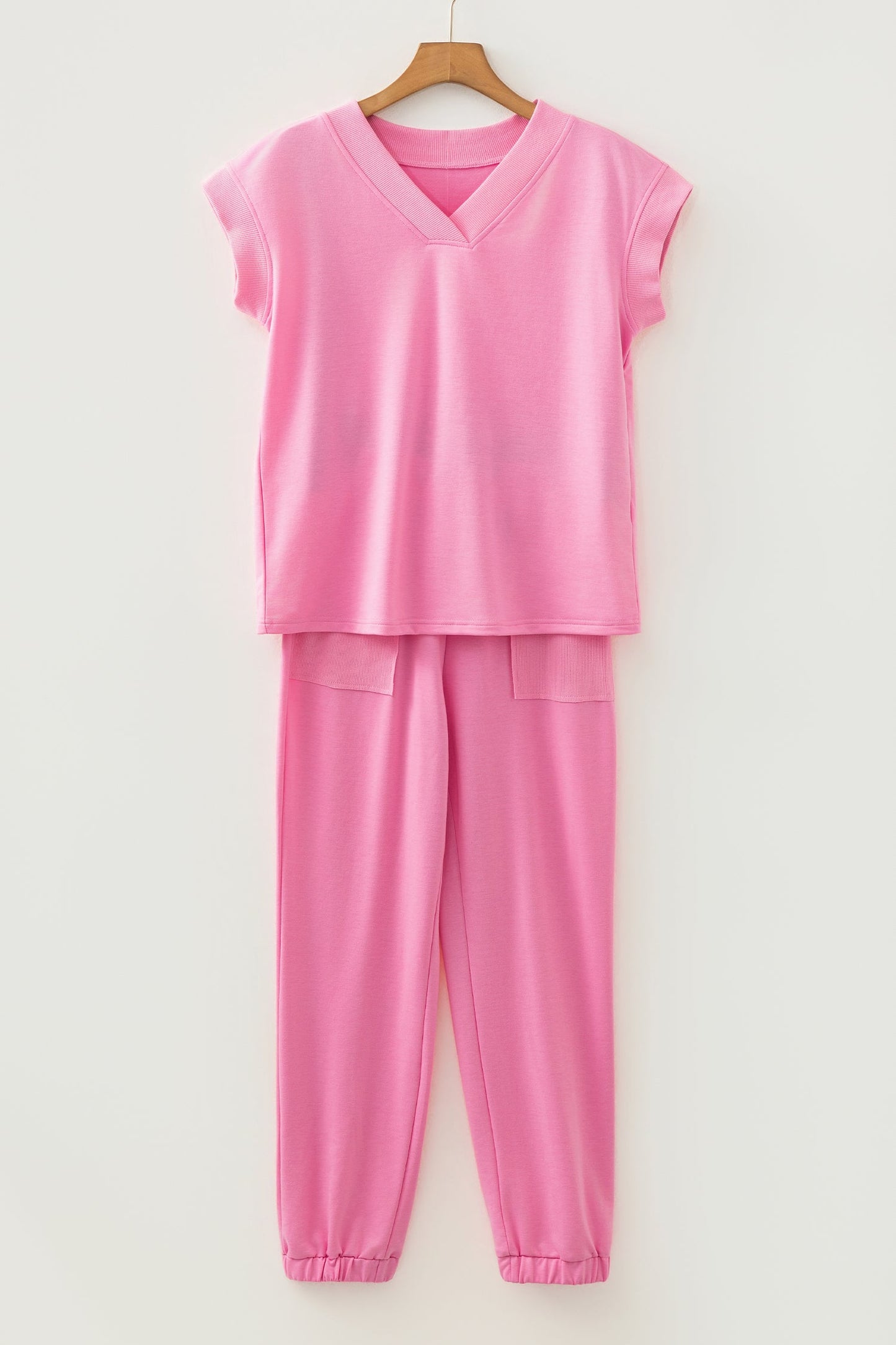 Pink outfit with a top and pants on a hanger against a white background