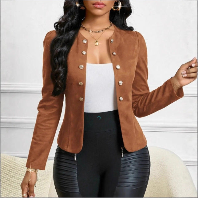 A woman wearing a cropped brown suede-like jacket with decorative metallic buttons, styled over a white top and black pants, posed indoors against a light wall.