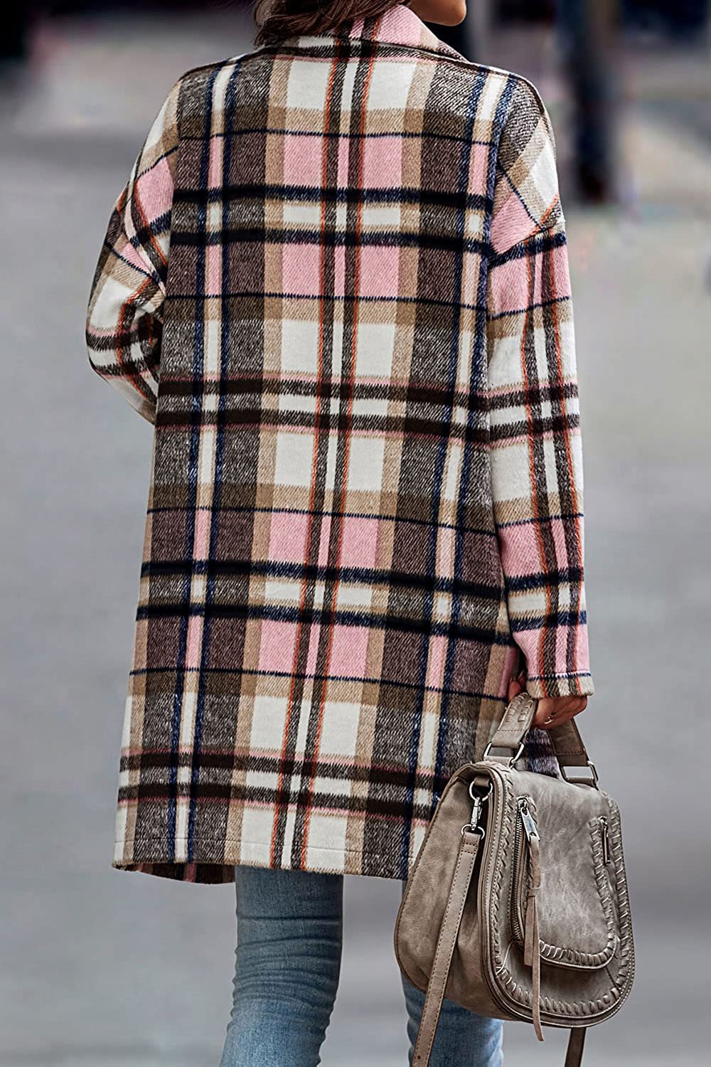 Person wearing a plaid coat holding a brown handbag on a blurred street background