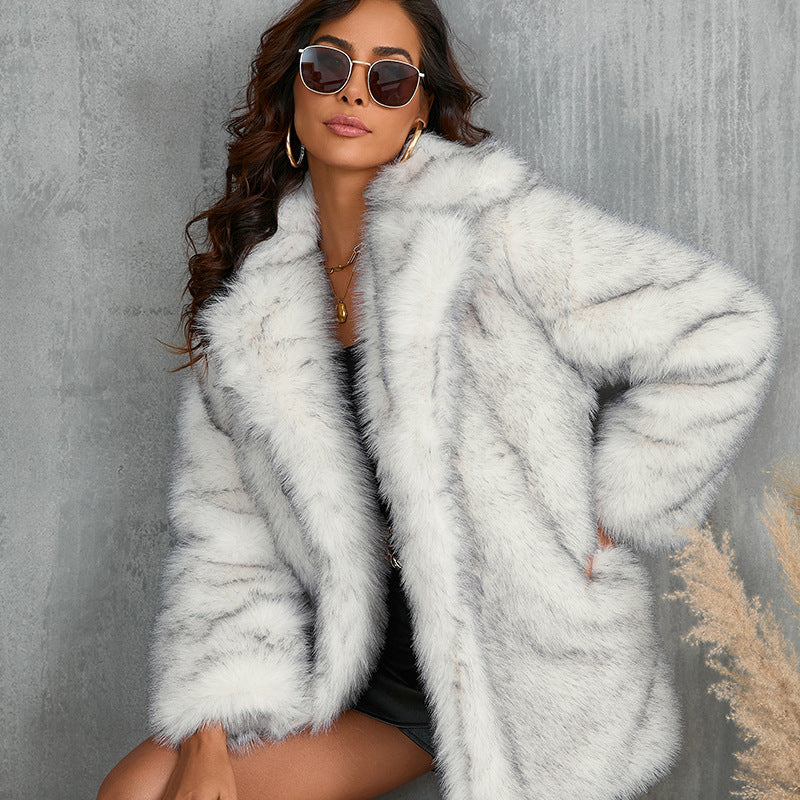 Woman wearing a light gray fur coat against a textured gray wall.