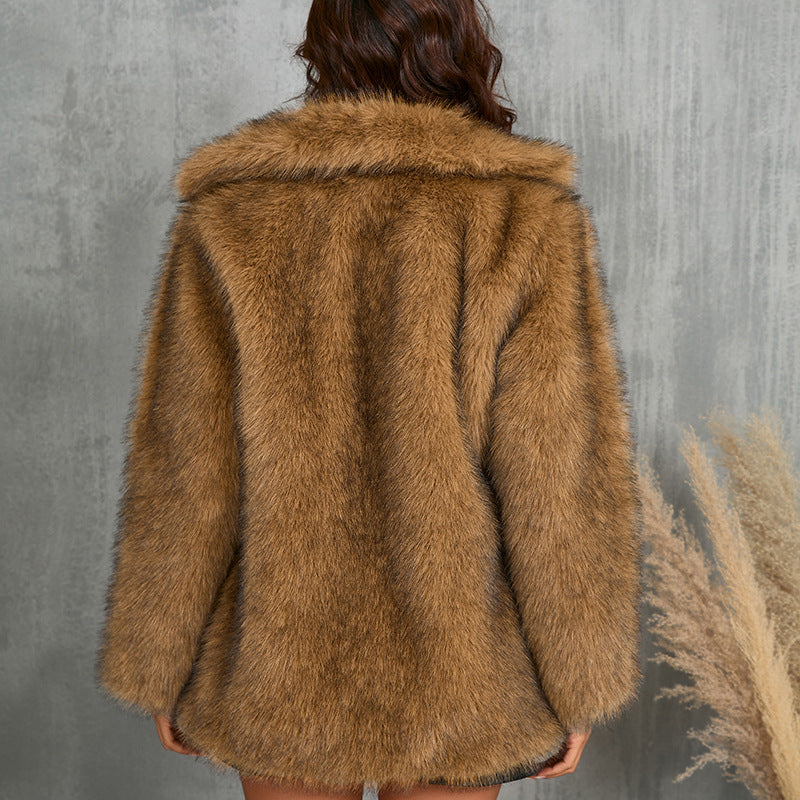 Brown fur coat worn by a person against a gray concrete wall.